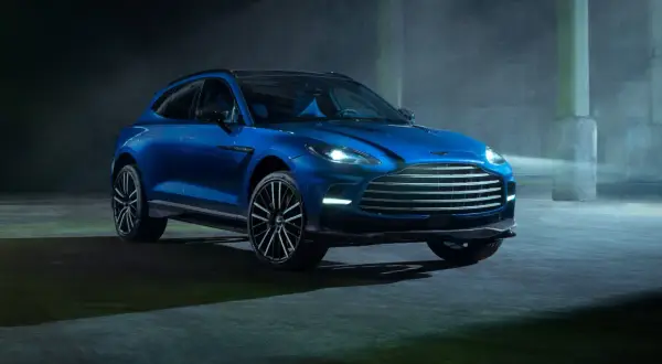 Niebieski Aston Martin DBX 707 lśni w półmroku, gotowy do podboju każdej drogi.