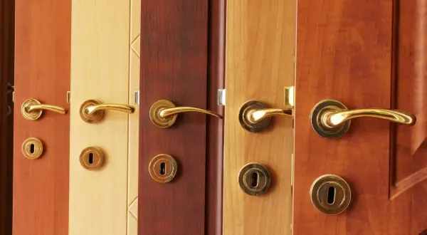 Plusieurs portes en bois aux teintes variées, chacune ornée d'une poignée dorée. L'idée de peindre une porte en bois prend tout son sens devant cette diversité.