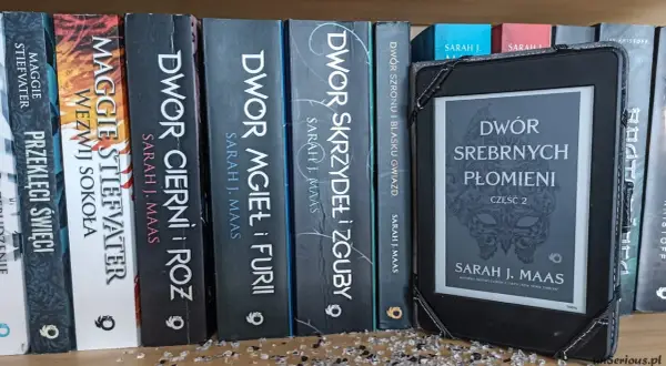 Na półce stoją książki z serii **Dwór Cierni i Róż** autorstwa Sarah J. Maas, obok e-czytnik z okładką "Dwór Srebrnych Płomieni".
