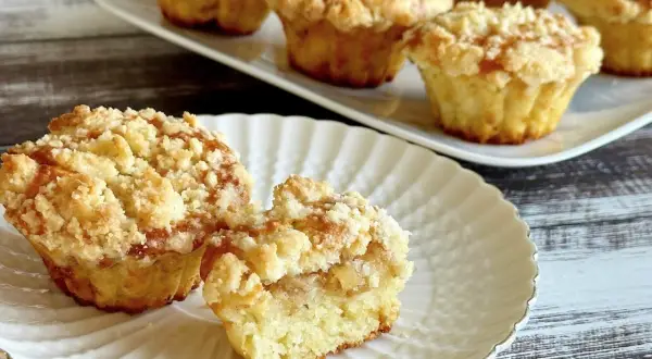 Pyszne muffinki z jabłkami, z kruszonką na wierzchu, prezentowane na białym talerzyku.