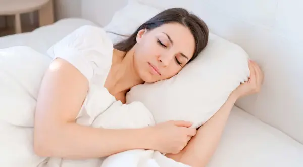 A woman sleeps peacefully, finding comfort and rest. This image illustrates how to sleep with vertigo, suggesting a serene and undisturbed slumber.