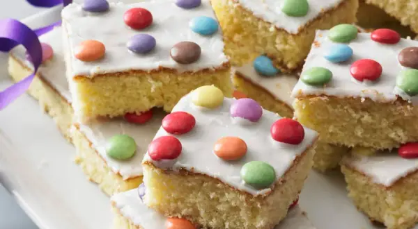 Bunte Smarties-Kuchenstücke auf einem Teller, ein leckeres fantakuchen rezept für Kindergeburtstage.