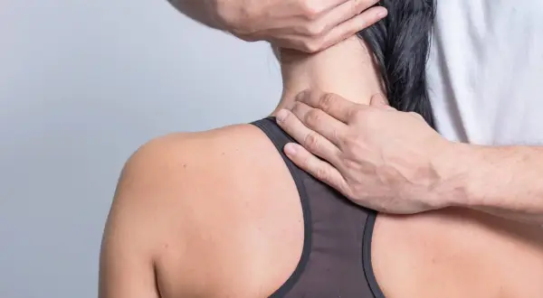 Hände massieren den verspannten Nacken einer Frau.