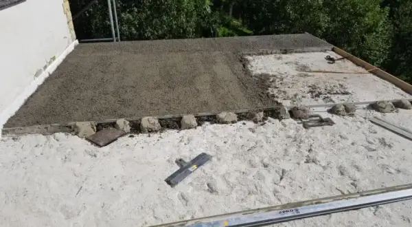 Budowa dachu z wykorzystaniem styrobetonu. Widać świeżo wylany materiał, który czeka na dalsze prace. Kluczowe są odpowiednie proporcje styrobetonu.