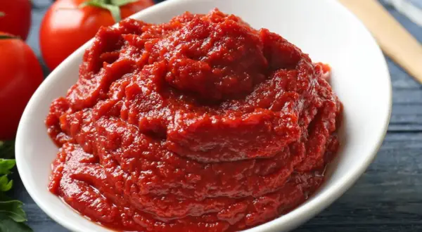 Schüssel mit selbstgemachtem Tomatenmark, daneben frische Tomaten.