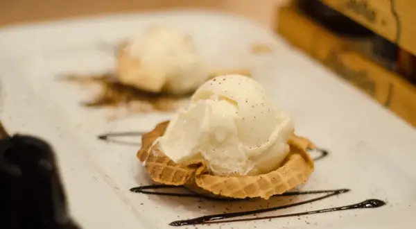 Dwa gałki lodów waniliowych w wafelku, ozdobione czekoladą. Idealne, nowoczesne desery.