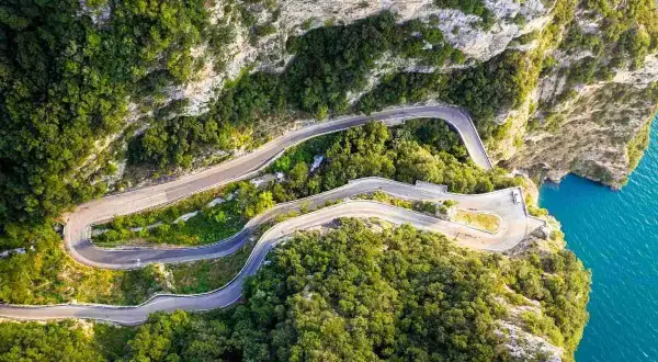 La strada della forra serpeggia tra rocce e vegetazione lussureggiante, con curve mozzafiato a picco sul mare turchese.