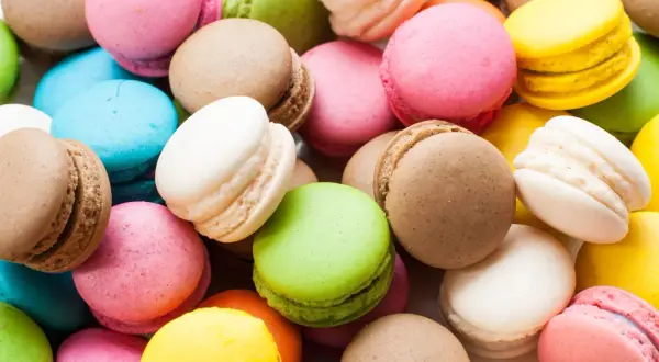 Montón de macarons de colores: rosa, verde, amarillo, azul, blanco y marrón. Estos dulces, de donde son los macarons, son un deleite visual y gustativo.