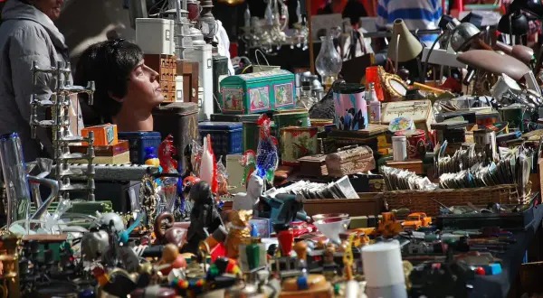 Buntes Treiben auf dem Flohmarkt Kelheim: Ein Kopf einer Schaufensterpuppe blickt neugierig in die Menge, umgeben von allerlei Trödel und Schätzen.