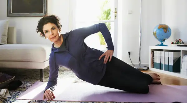 Frau macht seitlichen Unterarmstütz auf einer Matte. Nach dem Training gibt es gesunde exercise snacks.