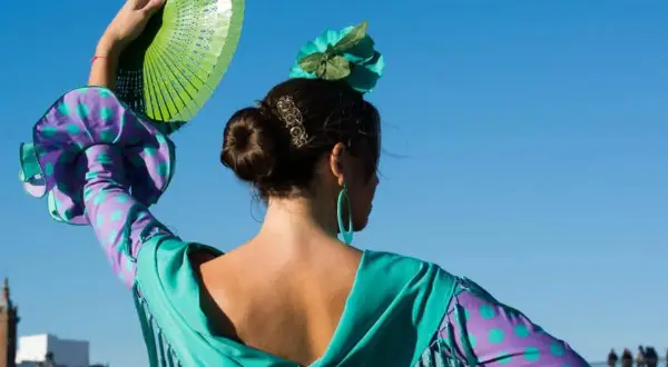 Bailarina de flamenco con abanico verde, evocando el flamenco origine. Su vestido vibrante y flor en el pelo resaltan la pasión.