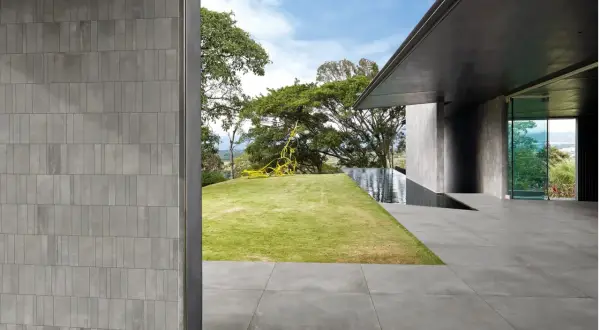 Pareti e pavimenti in gres 2 cm creano un'atmosfera moderna, con piscina a sfioro e scultura gialla in giardino.