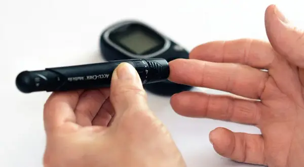 Osoba przygotowuje się do pobrania próbki krwi glukometrem. To ważny krok w monitorowaniu cukrzycy, który może pomóc w uniknięciu bólu i innych dolegliwości, podobnie jak skuteczny lek przeciwbólowy.
