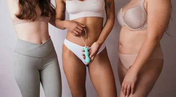 Trois femmes posent ensemble. Celle du milieu tient un appareil pour la rééducation de la vessie femme.