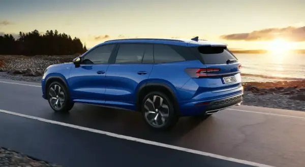 Niebieski Skoda Kodiaq jedzie wzdłuż wybrzeża o zachodzie słońca. Poznaj jego imponujące skoda kodiaq wymiary.