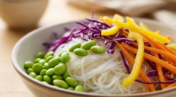 Schüssel mit Glasnudeln, Edamame, Rotkohl, Karotten und gelbem Paprika. Sind Glasnudeln gesund? Ja, sie sind eine leichte und nährstoffreiche Option.