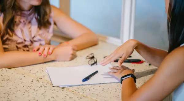 Twee vrouwen bespreken papieren. Mogelijk gaat het over de hsp therapie vergoeding.