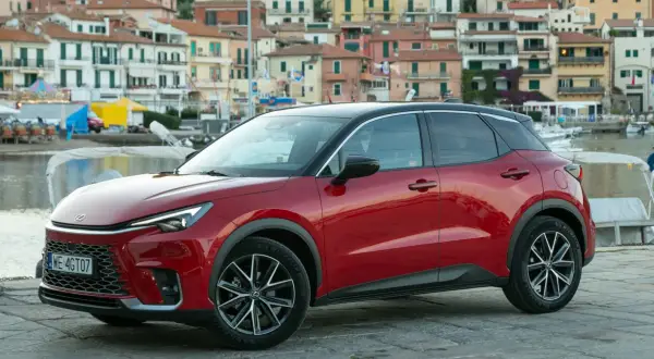 Czerwony Lexus LBX na tle nadmorskiego miasteczka. Sprawdź, jaka jest lexus lbx cena i zacznij planować wakacje!