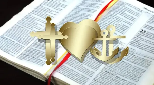 Złoty krzyż, serce i kotwica na otwartej Biblii. Te symbole wiary, nadziei i miłości, jak katarzy, wskazują drogę.