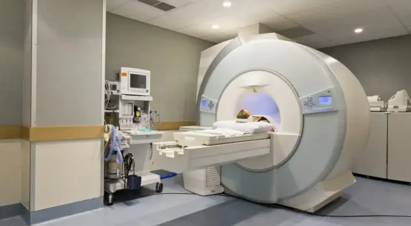 Pacjentka leży w aparacie do rezonansu magnetycznego. Obok stoi aparat do monitorowania parametrów życiowych.