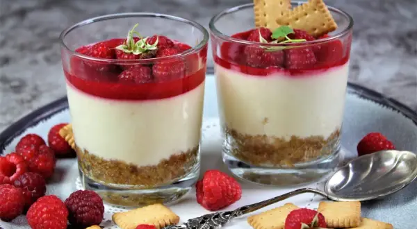 Zwei leckere Desserts im Glas mit Himbeeren und Keksen, ein süßer Genuss für jeden Anlass.