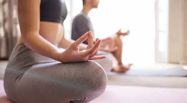 Zwei Personen praktizieren Yoga in Lindlar. Sie sitzen im Lotussitz auf Yogamatten, die Hände in Mudras.