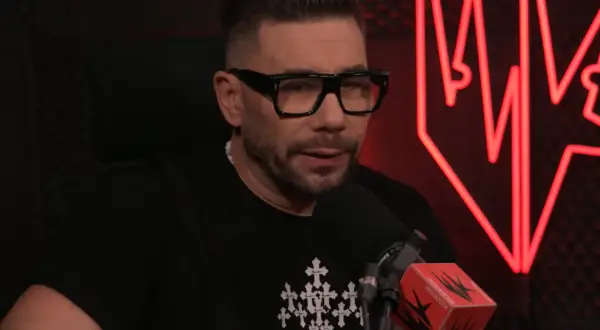 Mężczyzna w okularach i czarnej koszulce z krzyżami, kto prowadzi szalony podcast.