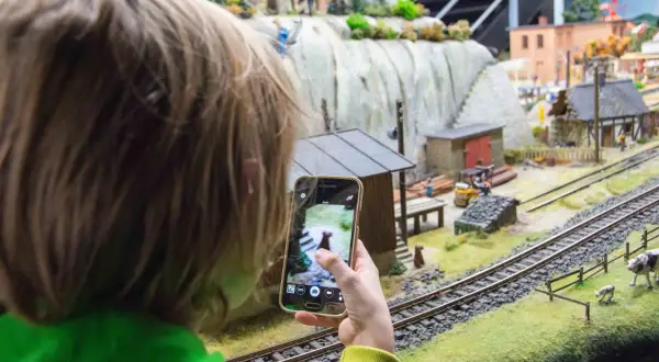 Dziecko fotografuje telefonem miniaturową wioskę w parku miniatur Wrocław.