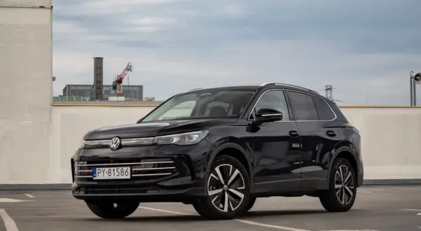 Czarny Volkswagen Tiguan 2020 na parkingu, z widocznym fragmentem miasta w tle.
