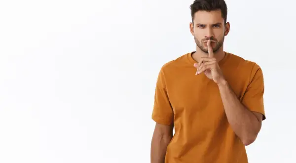 Uomo con dito sulle labbra, sguardo intenso. Un chiaro messaggio: quando un uomo ti dice lasciami in pace, è meglio ascoltare.