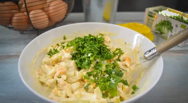 Cremiger eiersalat mit schmand, garniert mit frischen Kräutern und Frühlingszwiebeln. Perfekt für ein leichtes Mittagessen.