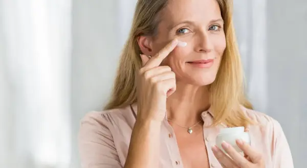 Frau trägt Vitamin A Kosmetik auf, um ihre Haut zu pflegen.