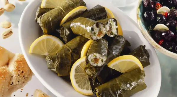 Gefüllte Weinblätter, ein köstliches Dolmades Rezept, serviert mit Zitronenspalten und Oliven.