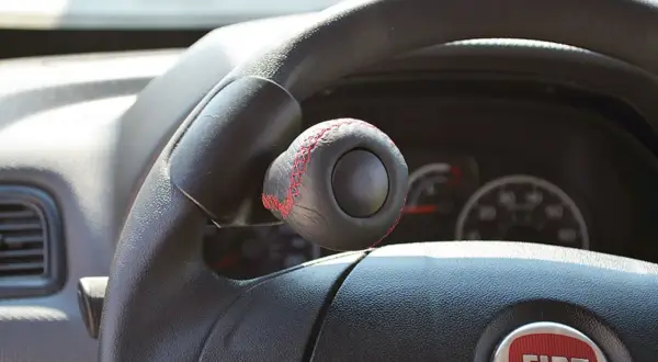 Pomello volante in pelle nera con cuciture rosse, un accessorio che rispetta la normativa per una guida sicura e personalizzata.