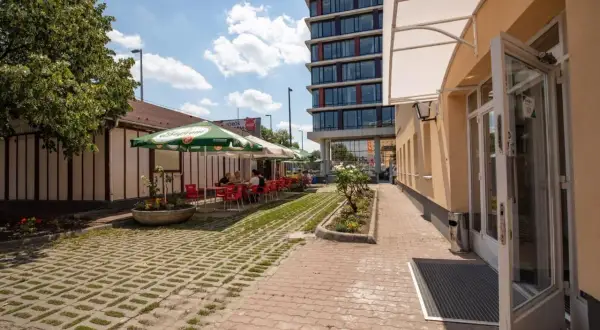 Letni dzień w kawiarni przy budapest nepliget. Stoliki pod parasolami, ludzie odpoczywają.