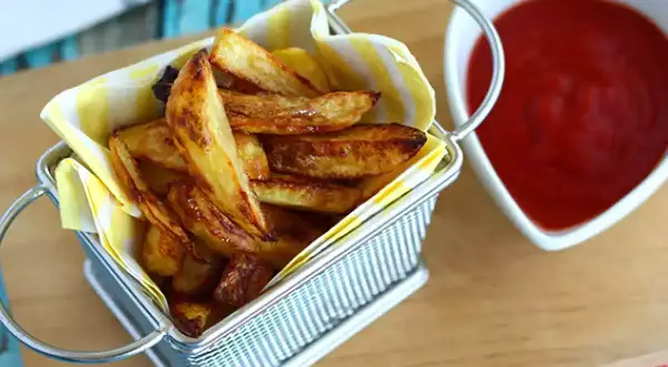 En korg med gyllene pommes frites, redo att doppas i ketchup. Perfekt för en mysig kväll.