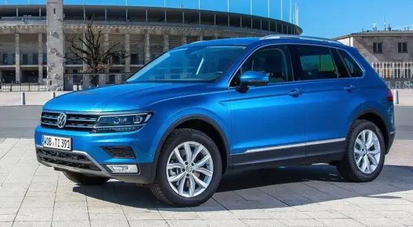 Niebieski VW Tiguan Allspace parkuje przed stadionem.