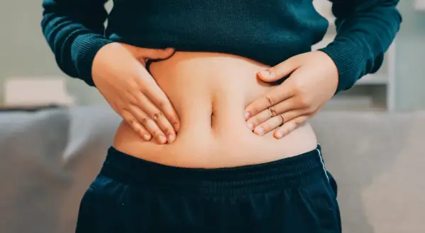 Mani che stringono la pancia, che nonostante sia magra, appare gonfia e dura.