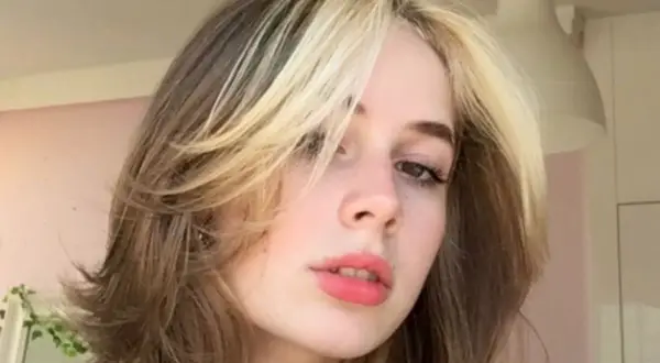 Dziewczyna z modnym wolf cut bez grzywki, z pasemkami blond na ciemniejszych włosach.