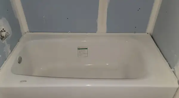 Installing cement board around a tub is underway. The tub is in place, and the blue drywall is being prepped for the next steps.