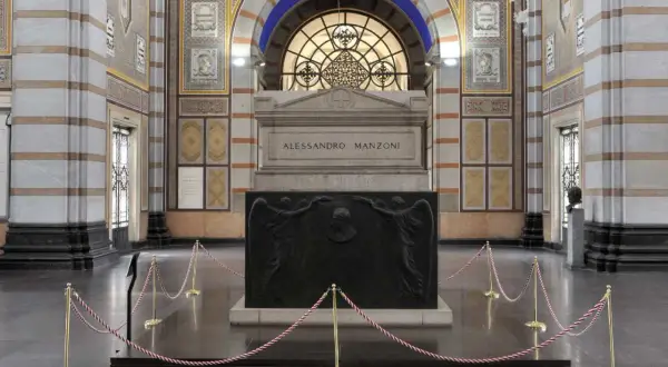 La tomba di Manzoni, imponente monumento con bassorilievi di angeli e ritratto, è protetta da cordoni dorati.