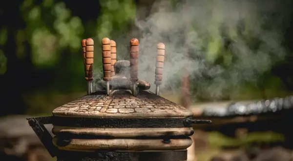 Dym unosi się z glinianego pieca tandoori, gdzie przygotowywane są aromatyczne potrawy.