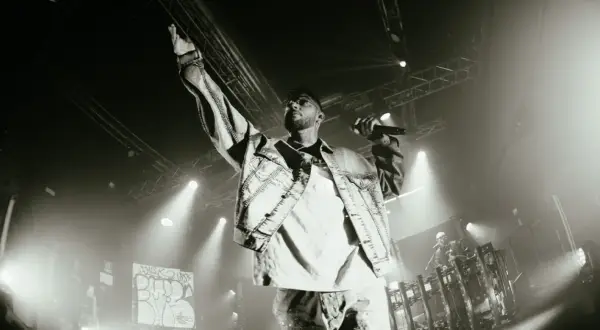 Emis Killa sul palco, con la mano alzata e il microfono in pugno, interpreta i suoi testi, parole di ghiaccio che riscaldano la folla.