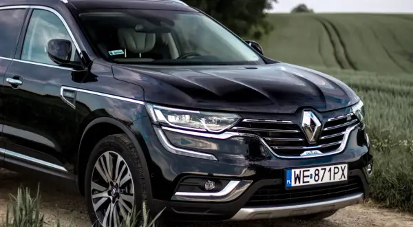 Czarny Renault Initiale na tle zielonych pól. Elegancki SUV z chromowanymi detalami i nowoczesnymi światłami.