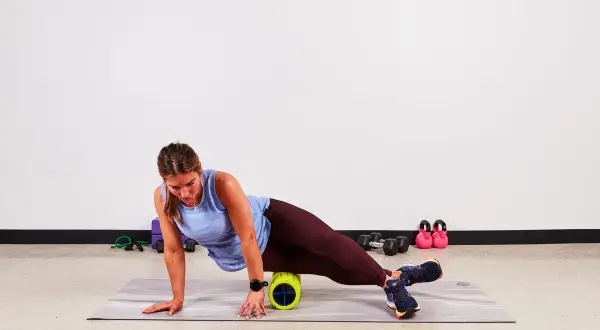 Donna usa un foam roller per alleviare la bandelletta ileotibiale. Soluzioni per il recupero muscolare.
