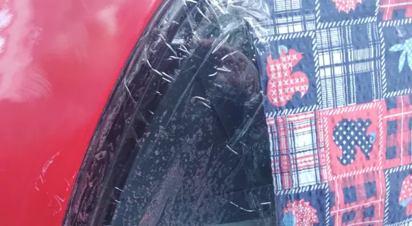 Czerwony lakier samochodu z folią ochronną i kolorową tkaniną z motywem zwierząt. To dowód, że lakierowanie samochodu zrób to sam może być kreatywne.