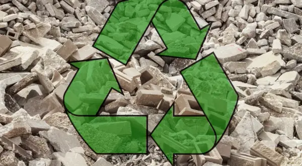 Símbolo de reciclaje verde sobre un montón de escombros de hormigón reciclado.
