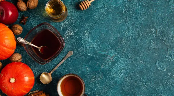 Jesienne składniki: dynie, jabłka, orzechy, cynamon i syrop pumpkin spice w miseczce.