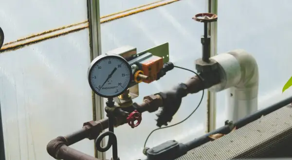 Manometr wskazuje niskie jakie ciśnienie na piecu gazowym. Rury i zawory są częścią instalacji.
