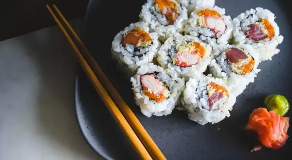 Talerz z sushi, pałeczki i dodatki. Zastanawiasz się nad sushi kcal? Smacznego!